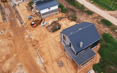 Suburb house construction, aerial viev. Home construction of ceramsite blocks. Construction site of building a country houses. Construction work of laying bricks, gas silicate blocks and roof.