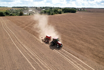Tractor sowing seed onto at field. Planting Equipment and Farm Implements and Machine. Mini Agricultural tractor on seeds sowing at farmers country, aerial view. Farming and seeding concept.