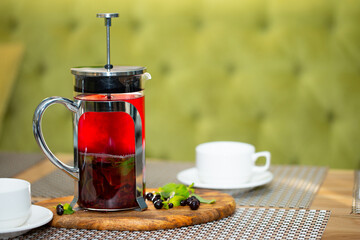 Berry tea in a cafe, vitamin drink in a transparent teapot on the table. Nice hot drink, delicious breakfast.