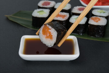 bamboo sticks dip a roll with fish in soy sauce close-up