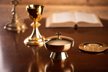 Catholic symbols composition. Religion concept. Holy Bible, rosary and golden chalice on the brown...