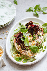 roasted radicchio salad with feta, green tahini, Pine nuts and basil pesto. Radicchio rosso di treviso tardivo, italian red chicory. Healthy Meal recipe preparation. Plant-based dishes.