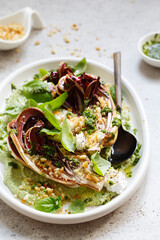 roasted radicchio salad with feta, green tahini, Pine nuts and basil pesto. Radicchio rosso di treviso tardivo, italian red chicory. Healthy Meal recipe preparation. Plant-based dishes.