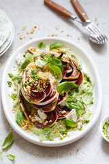 roasted radicchio salad with feta, green tahini, Pine nuts and basil pesto. Radicchio rosso di treviso tardivo, italian red chicory. Healthy Meal recipe preparation. Plant-based dishes.