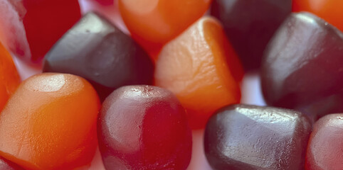 Selective focus.Close-up texture of red, orange and purple multivitamin gummies on white background