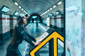 Fashion Style Model Female Of 20s Posing on Subway Station Platform. Gorgeous Brunette Woman Looks at the Metro Map in the Platform of the Empty Station. Close-up