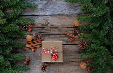 gift box, cinnamon sticks, nuts, cones and fir tree branches on old wooden background. New year and Christmas holidays concept. festive winter season. flat lay