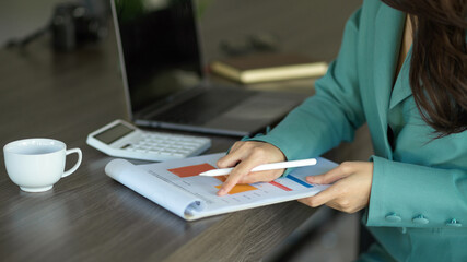 Confident businesswoman working on financial data report at her desk.