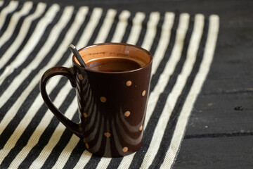 a cup of coffee is on the table in the kitchen on a striped tablecloth in the morning, coffee