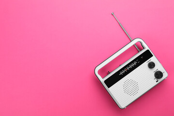 Retro radio receiver on pink background, top view. Space for text