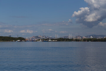 day view of the sea, islets, capes, white clouds and blue sky and the city on the hills in the background. Shot in the Novik harbor on island Russky in Vladivostok, Russia