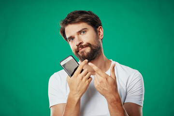 man in a t-shirt with a phone in his hand on a green background cropped view