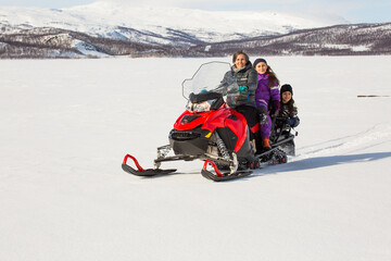 Mother with children on red snowmobile