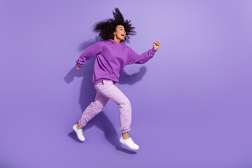 Full length profile photo of excited amazed girl running hurry look empty space isolated on purple color background