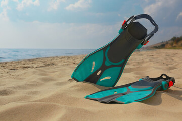 Pair of turquoise flippers on sandy beach near sea. Space for text © New Africa