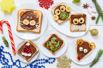 Assorted funny animals toasts with chocolate, fresh fruit, marshmallows on plates, top view. The idea of a menu for a children's party. Creative breakfast, Christmas theme.