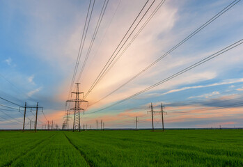 silhouette of high voltage power lines against a colorful sky at sunrise.