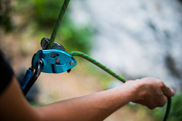 Man's hands operating a rock climbing belaying device