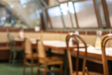 Blurred scene of empty table and chair set in the cafeteria which is ready to service for customer. Interior of business place background photo. 