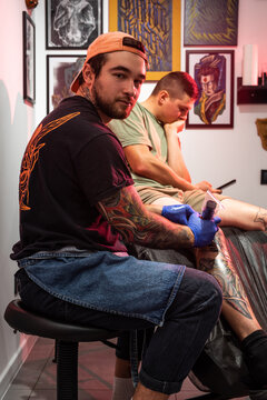 Tattoo artist creates new tiger head tattoo with tattoo skin painting machine on the leg of client at tattoo studio 