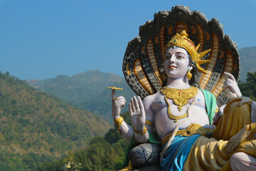 A sculpture of the Indian supreme god Vishnu on the banks of the Ganges River in Rishikesh - a...