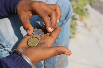 Indian beggar boy with different coins in his hands. Coins in the palm of the poor man.