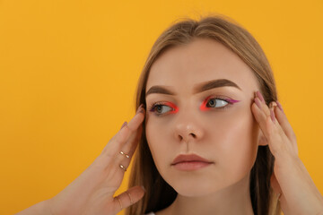 Fototapeta premium Beautiful model girl with makeup on yellow background