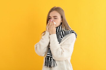 Sick girl on yellow background, seasonal cold concept