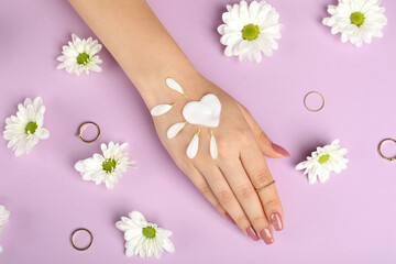 Concept of hand care on purple background with flowers