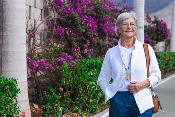 Portrait of elderly woman walking on  a flowered street.  Attractive senior woman smiling