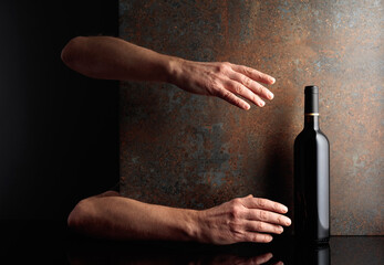 Hands reach for a bottle of red wine.