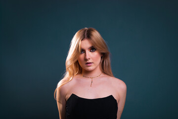 Young caucasian woman wearing all in black modeling in a photography studio with a blue dark background.