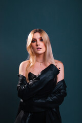 Fototapeta premium Young caucasian woman wearing all in black modeling in a photography studio with a blue dark background.