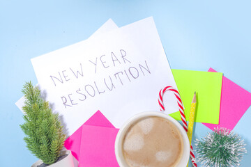 2022 new year resolution concept. Notepad with copy space for your year plan and action list, holiday decoration, latte coffee cup  on high-colored blue background flatlay top view copy space