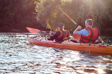 Happy young couple in sea vests kayaking on Danube river together. Having fun in leisure activity. Romantic and happy woman and man on the kayak. Sport, relations concept.