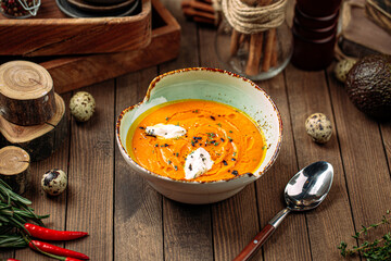 Gourmet lentil cream soup with herbs on wooden background