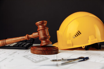 Judge wooden gavel and yellow helmet with construction plans