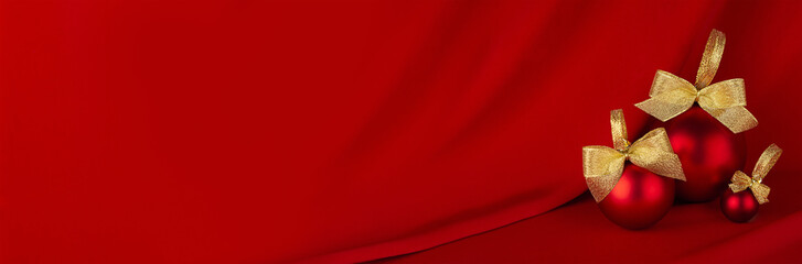 New Year banner in rich style with shiny red balls, golden bows on flowing deep scarlet silk...