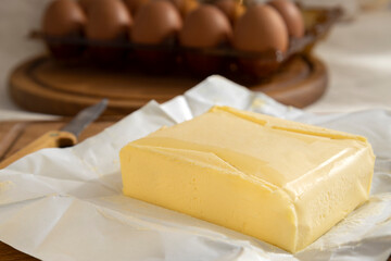 Closeup of piece of butter on the pack paper against fresh eggs.Ingredients for baking cake,biscuits