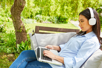 Business Frau mit Kopfhörer am Computer im Garten