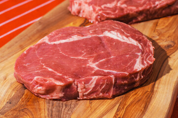 Two rib eye steaks on a wooden cutting board. Premium beef product. Fresh meat. Butcher craft and food supply industry.