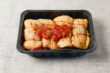 Raw corn fed chicken stuffed thighs wit herbs in a black plastic tray. The product has pronounced yellow color and special taste. Fresh poultry. Meat industry. Butcher craft and skill.