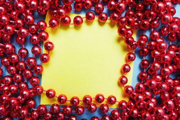 Obraz premium Yellow sticker note for a message framed with red beads. Christmas wish concept.