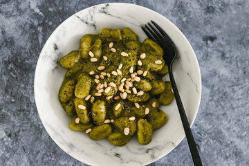vegan avocado basil pesto gnocchi with pine nuts topping, healthy plant-based food