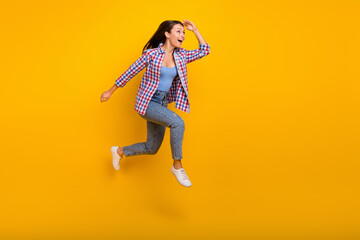 Full length profile photo of crazy inspired lady jump run look empty space wear plaid shirt isolated yellow color background