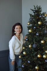 A beautiful girl is standing at the Christmas tree. New Year's mood. Merry Christmas