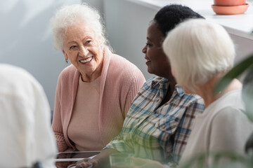Multiethnic elderly women with digital tablet talking in nursing home