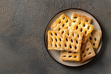 Puff cookies in a ceramic plate on a dark culinary background. Delicious homemade sweet pastries on the kitchen table top view
