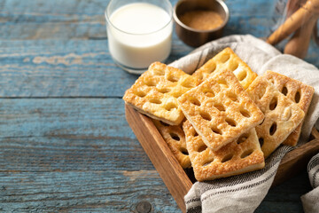 Puff cookies square in a wooden box on a blue wooden culinary background. Delicious homemade sweet pastries closeup