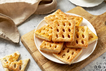 Puff pastry in a white plate on a light cooking table. Delicious homemade sweet pastries closeup
